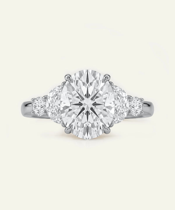 Oval diamond five-stone engagement ring with half-moon side diamonds on a platinum or white gold band.