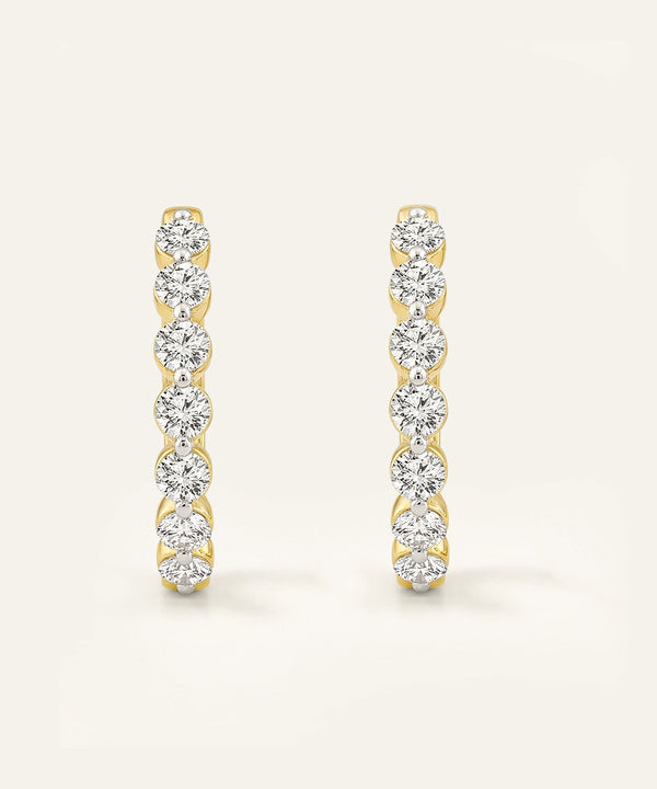 Pair of gold and diamond earrings on a light beige background