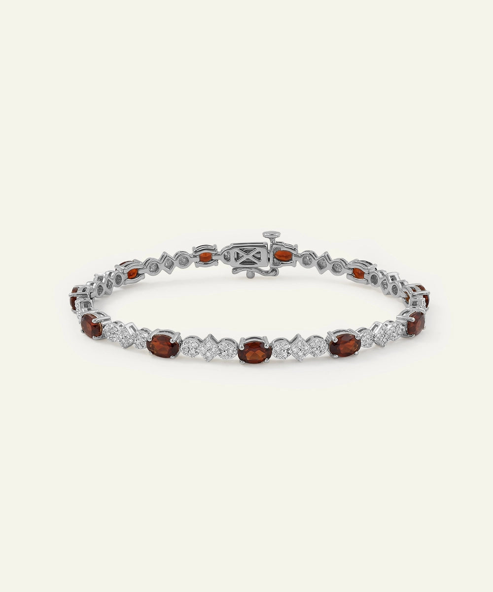 Silver bracelet with red gemstones on a white background
