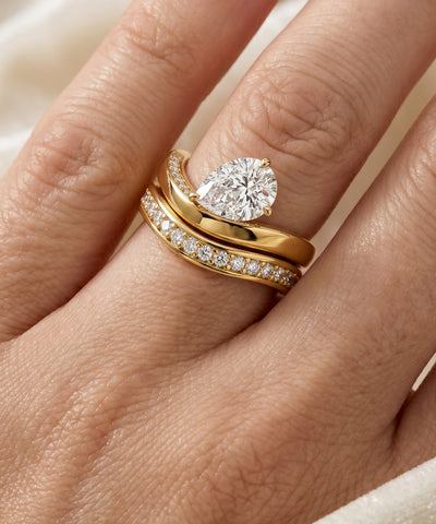Gold ring with a diamond on a hand against a neutral background - alternate view