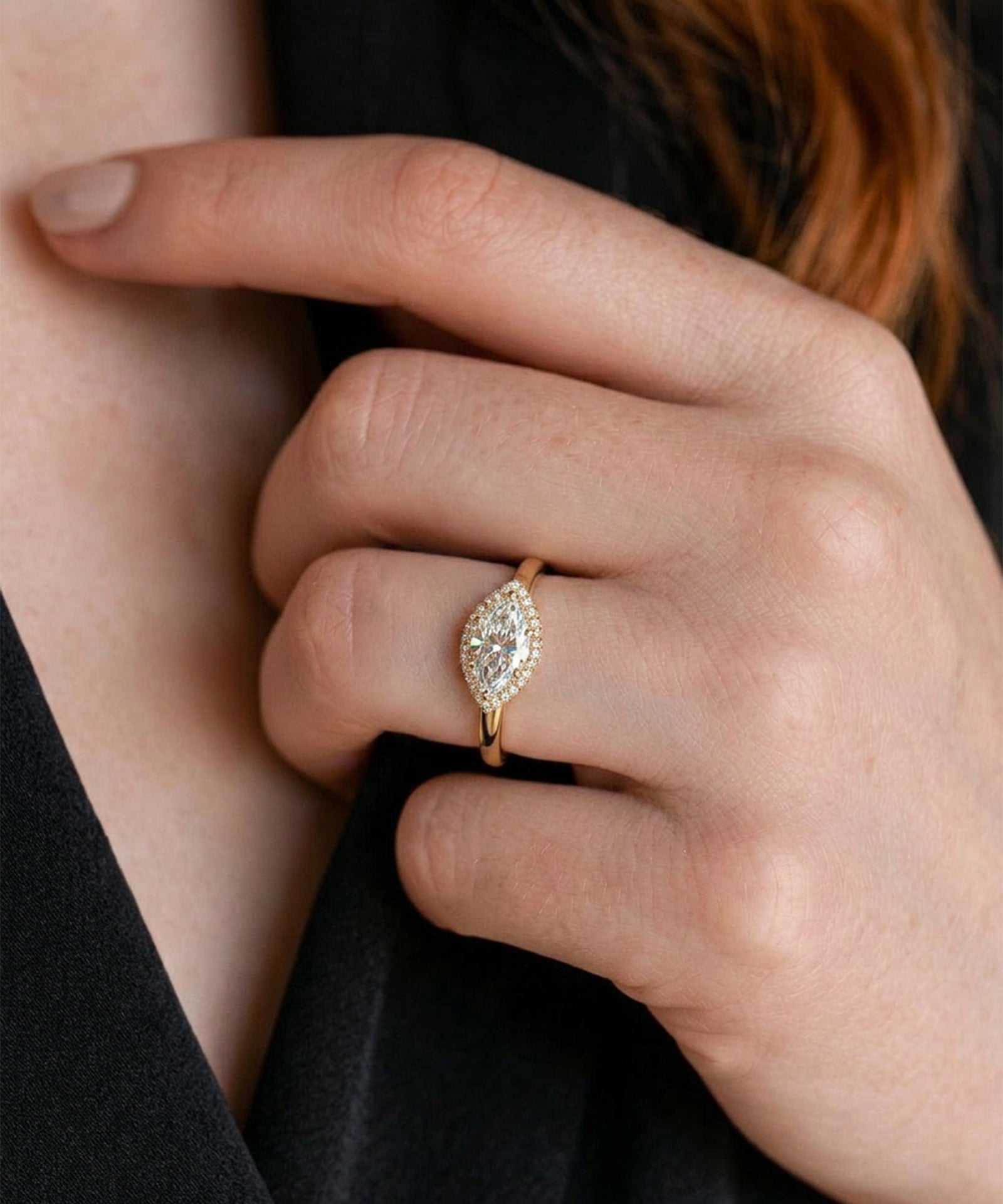 Close-up of a hand wearing a gold ring with a marquise-shaped diamond.
