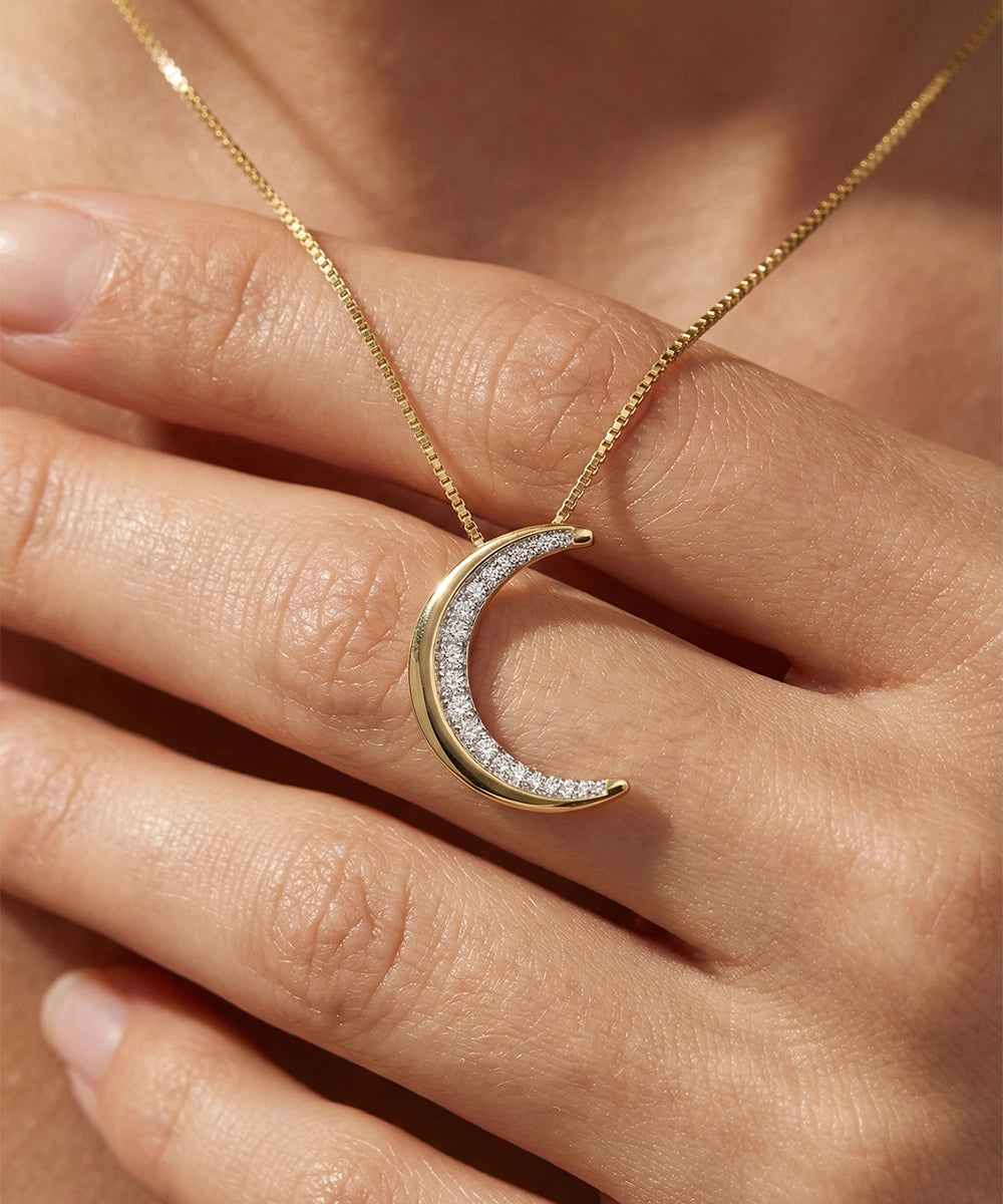 Gold crescent moon necklace with diamonds on a hand