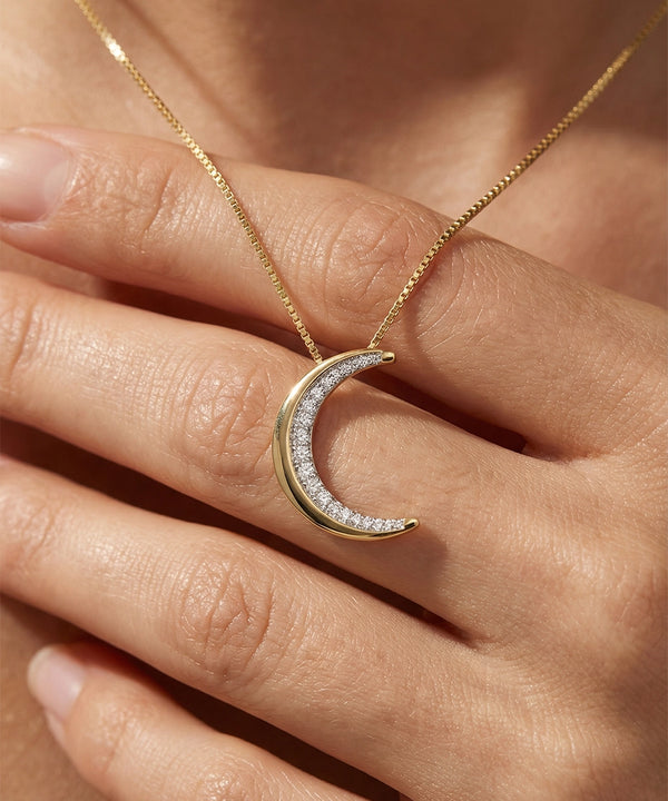 Gold crescent moon necklace with diamonds on a hand