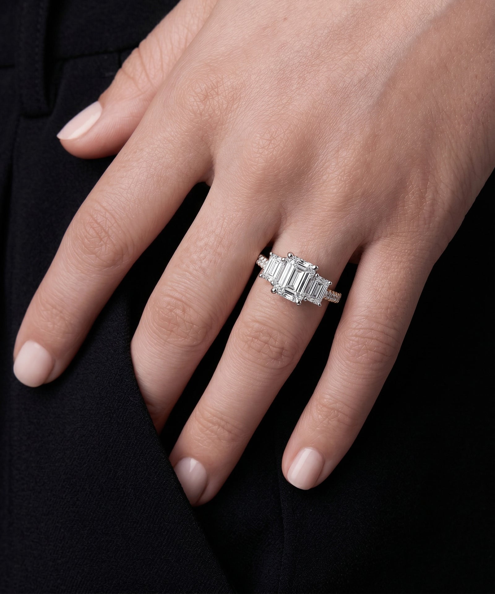Emerald-cut diamond five-stone ring with a pavé band on a hand.