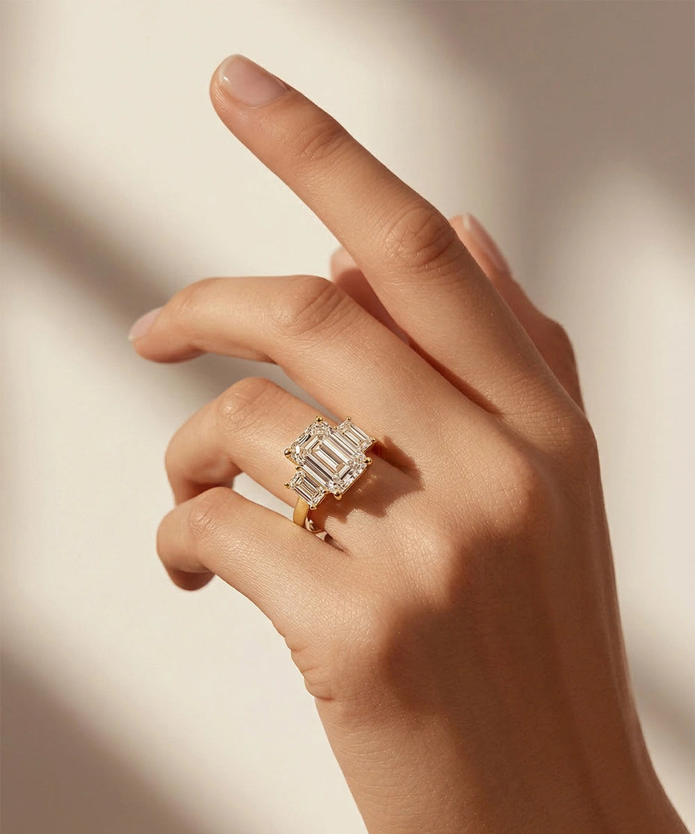 Hand wearing a gold ring with a large diamond on a neutral background