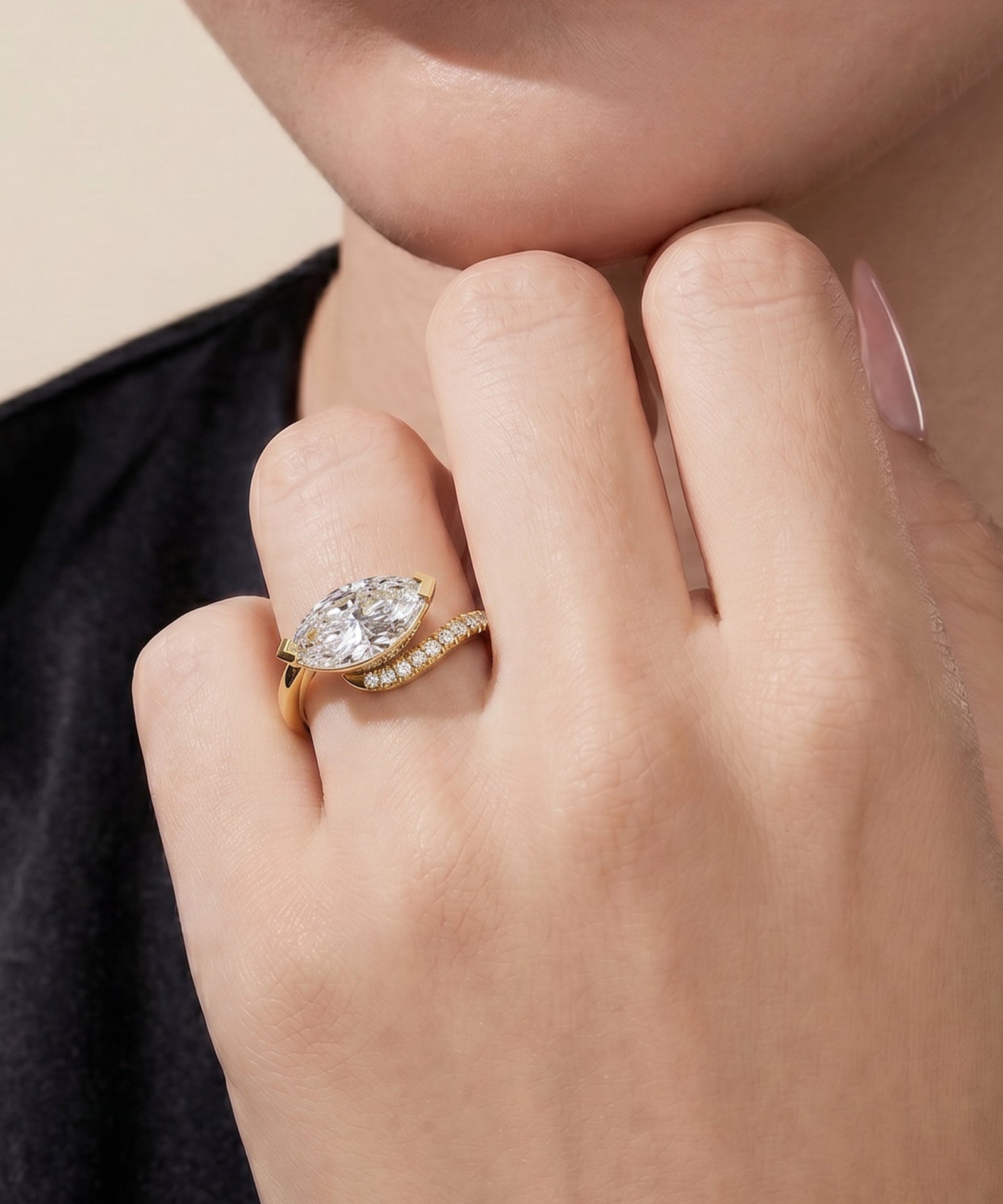 Close-up of a hand wearing a gold ring with a large diamond on a neutral background