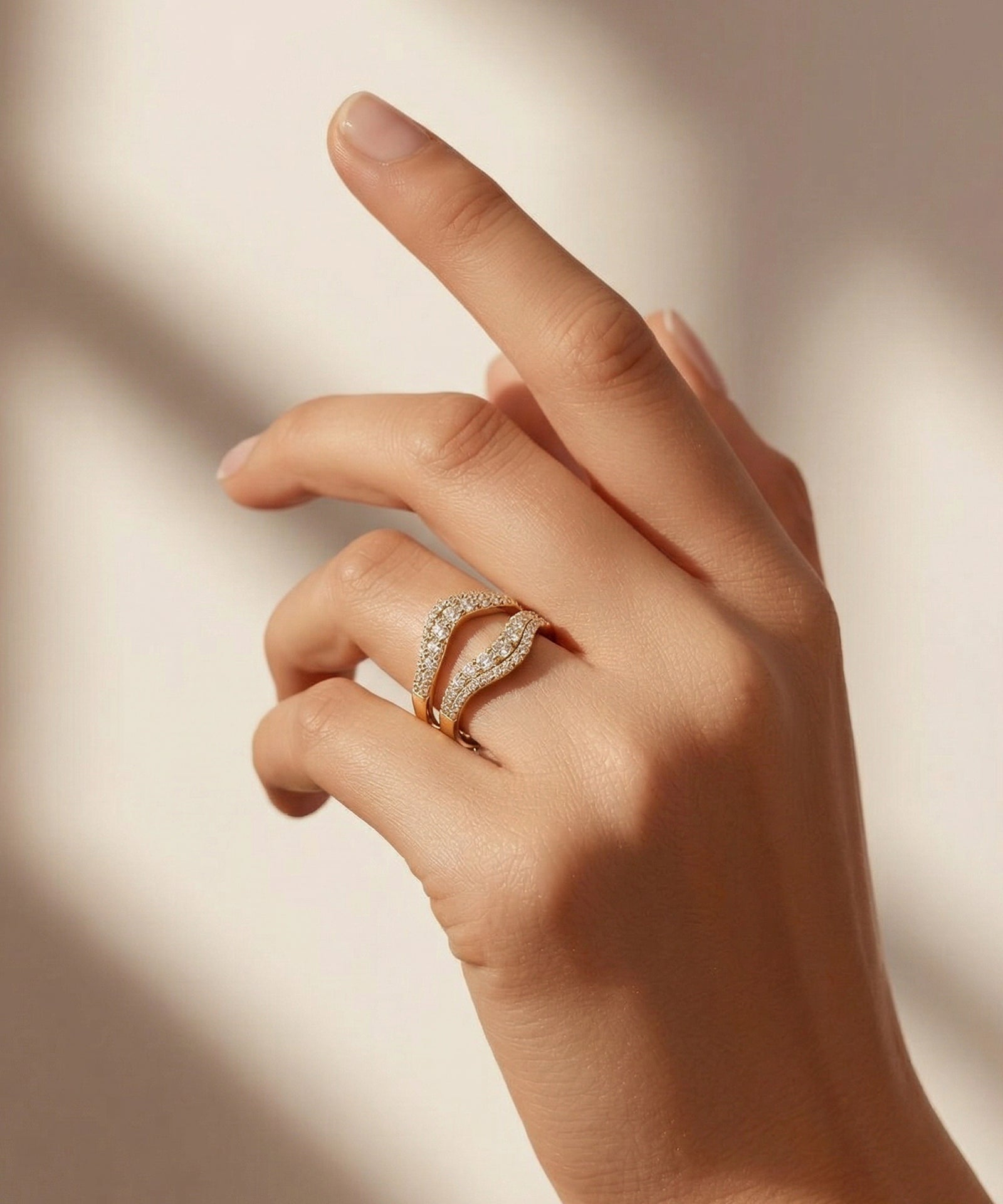 Hand wearing a gold ring with diamond accents on a soft background