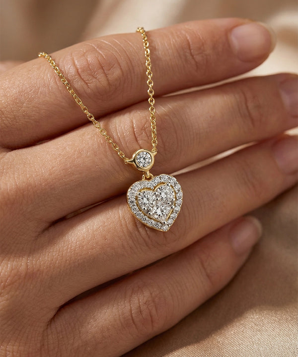 Gold necklace with a heart-shaped pendant on a hand against a beige background