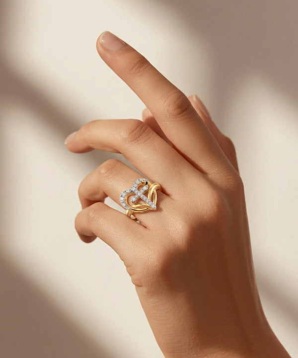 Hand wearing a gold ring with a heart design on a neutral background