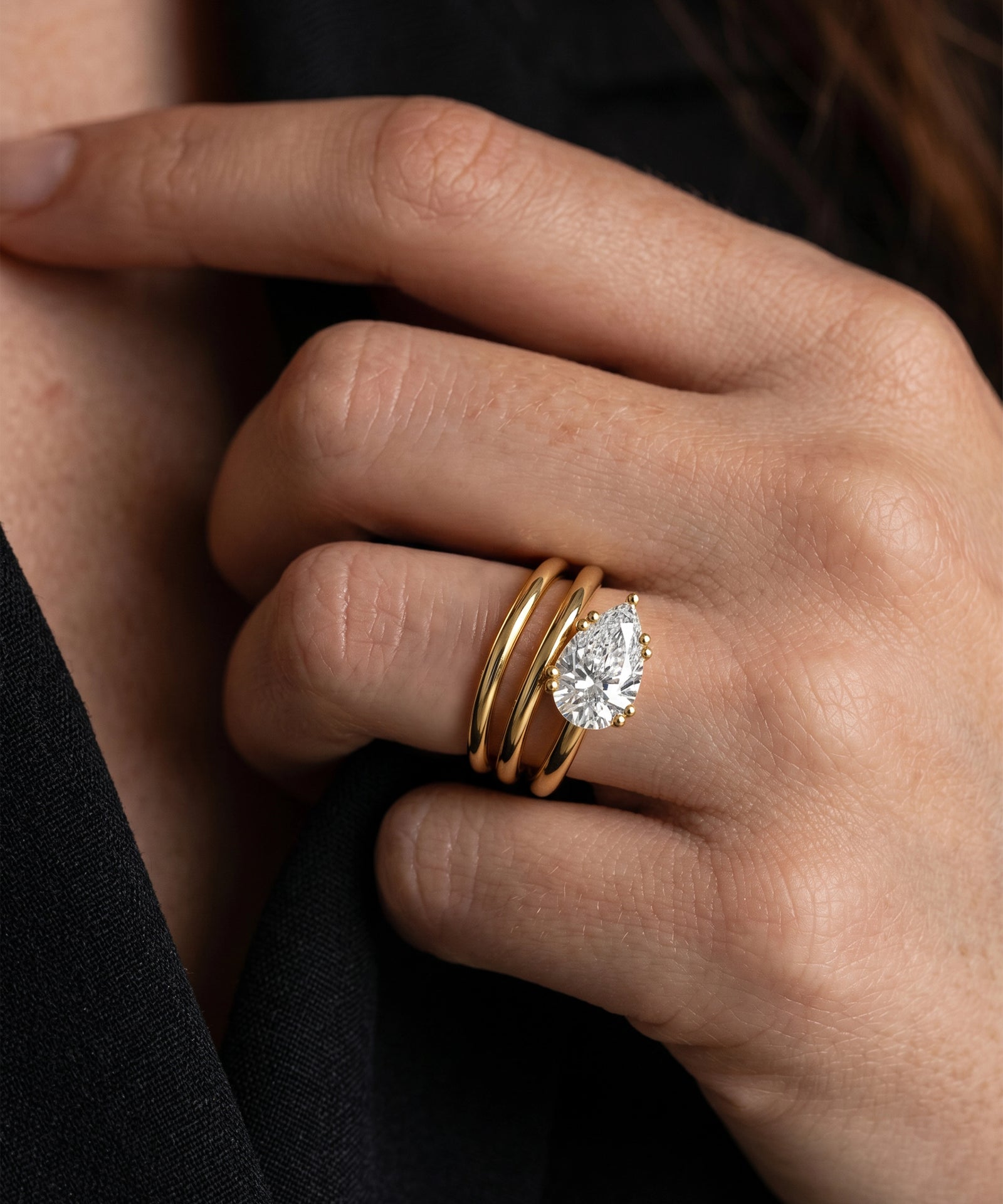 Close-up of a hand wearing two gold rings with diamond accents.