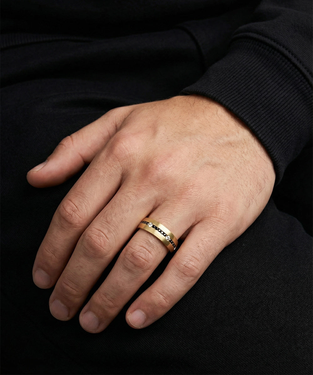 Hand wearing a gold ring with a black background
