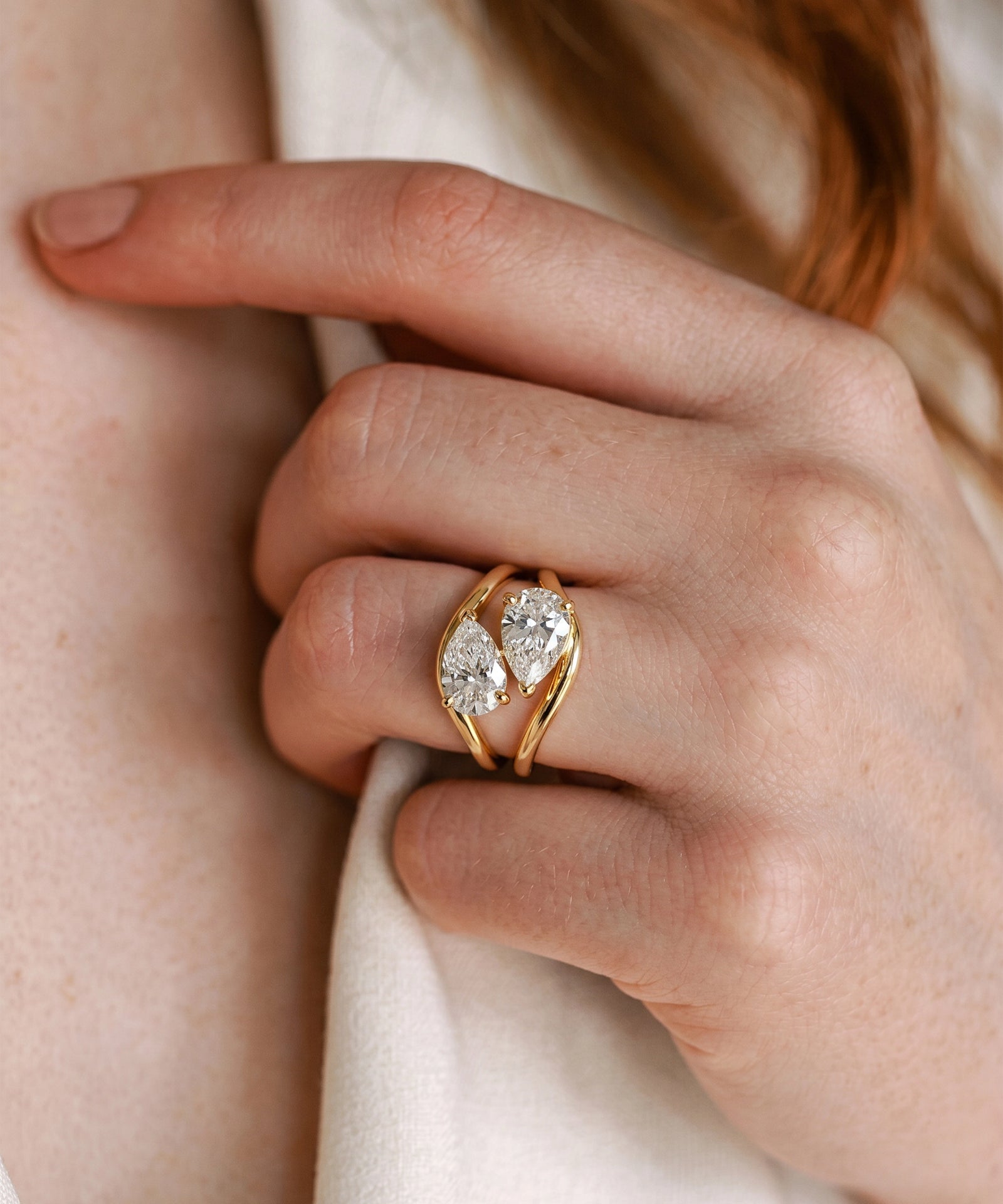 Gold ring with a diamond on a hand against a neutral background