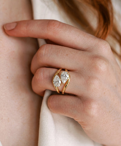 Gold ring with a diamond on a hand against a neutral background - alternate view