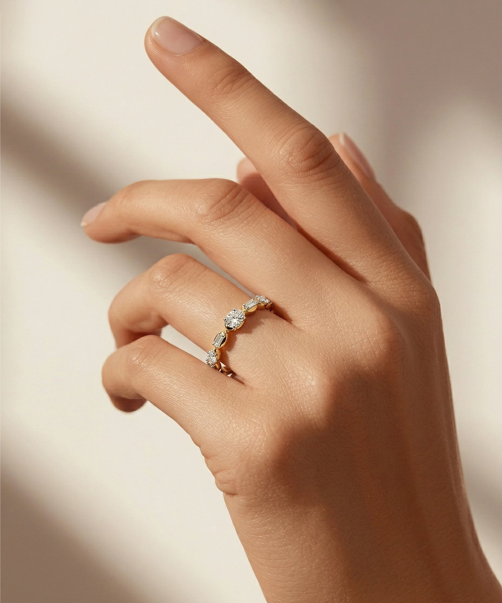 Hand wearing a diamond ring on a neutral background