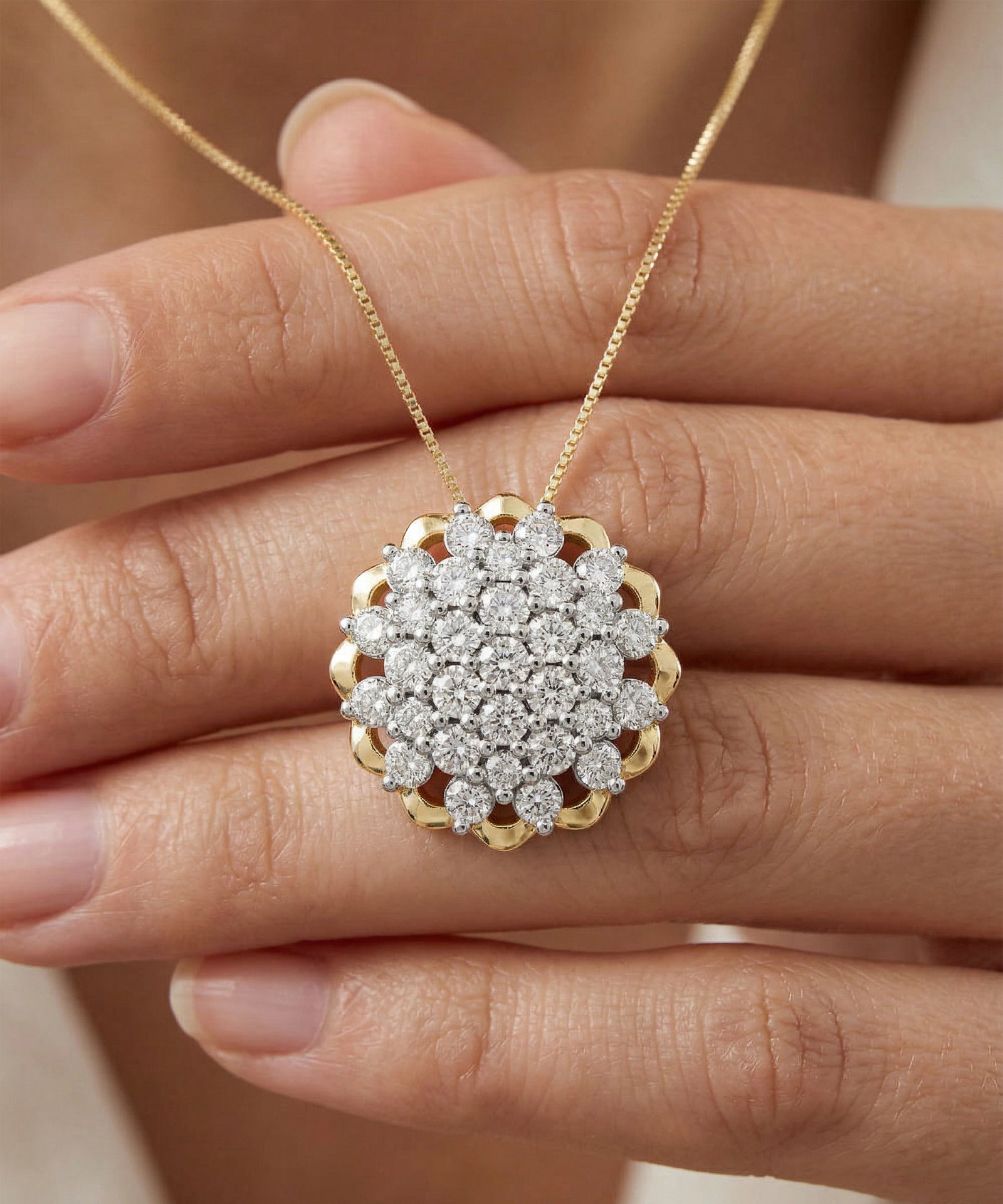 Gold necklace with a diamond pendant held by a hand against a neutral background