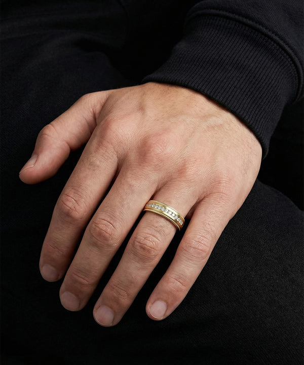 Hand wearing a gold ring with a black background