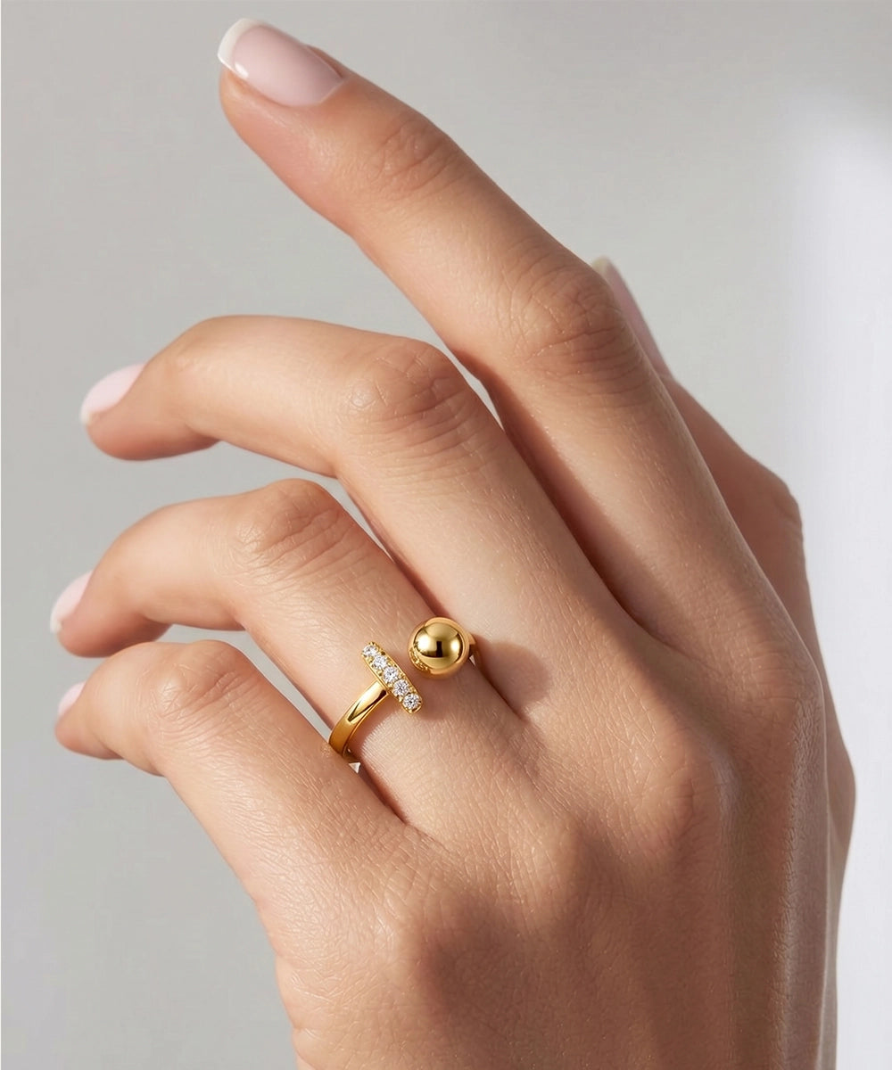 Hand wearing a gold ring with a small diamond on a neutral background