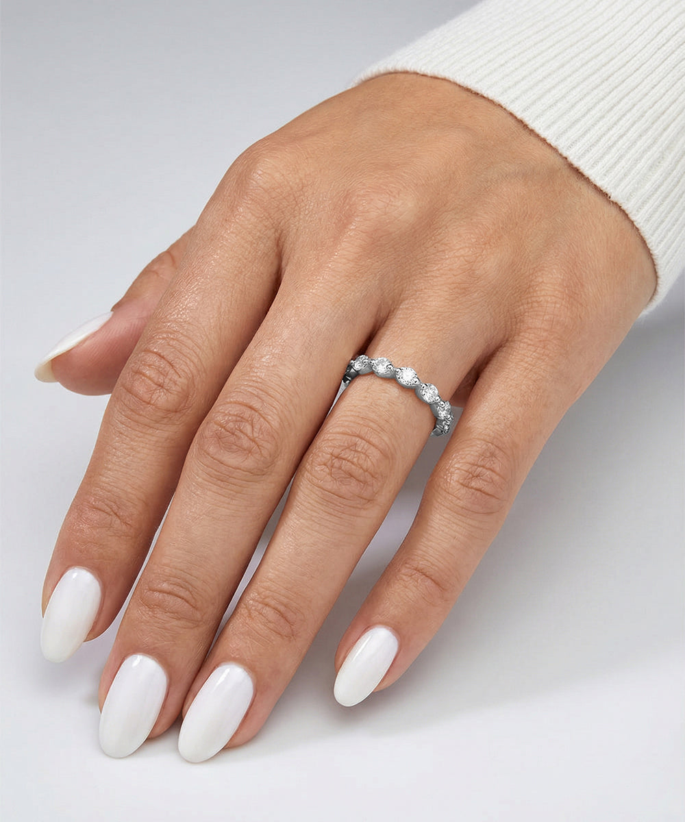 Hand wearing a silver ring with a diamond on a light gray background