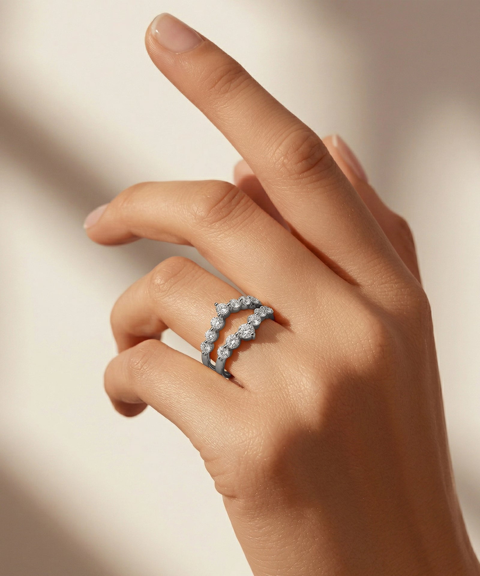 Hand wearing a diamond ring on a neutral background