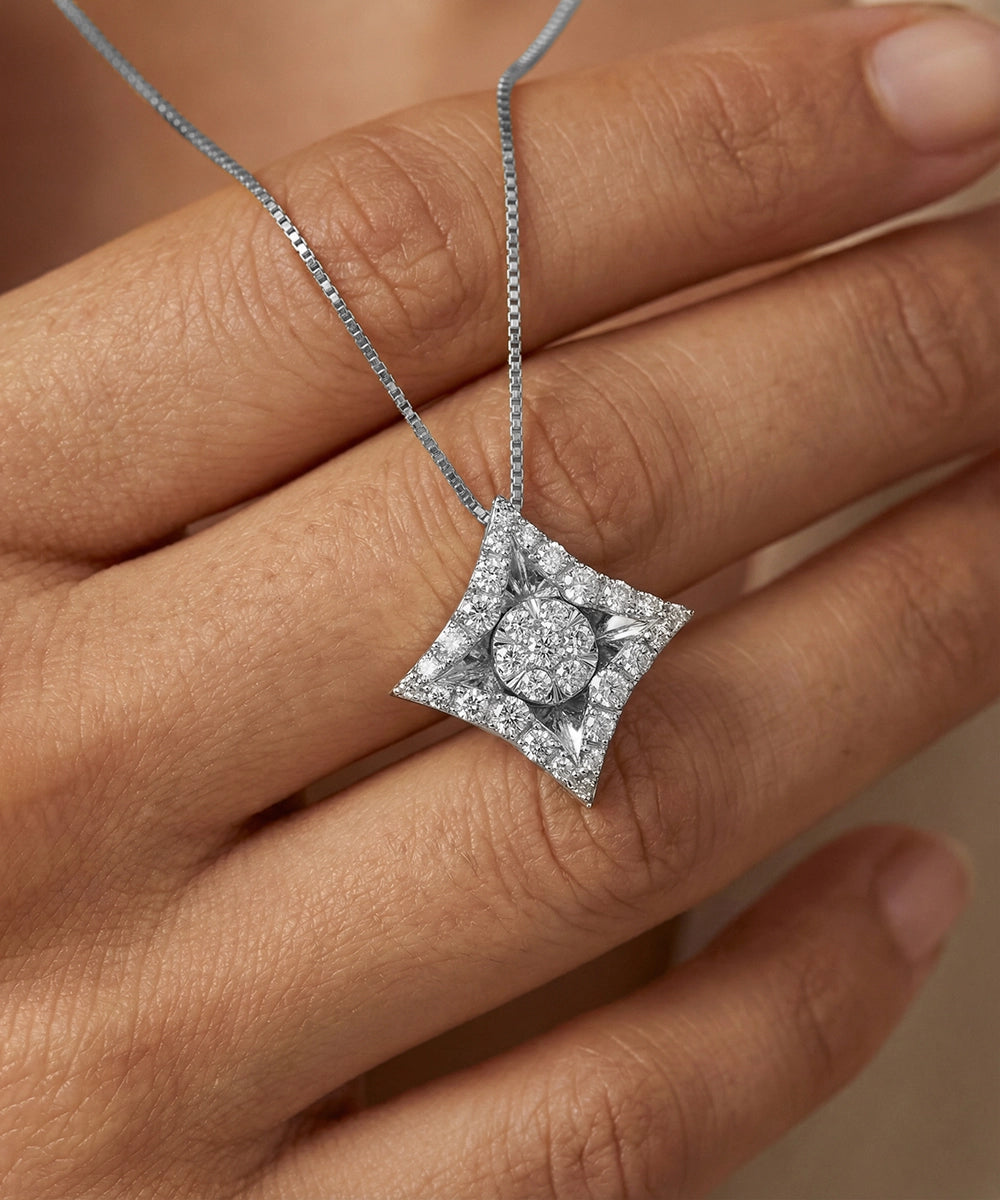 Diamond necklace held between fingers against a neutral background