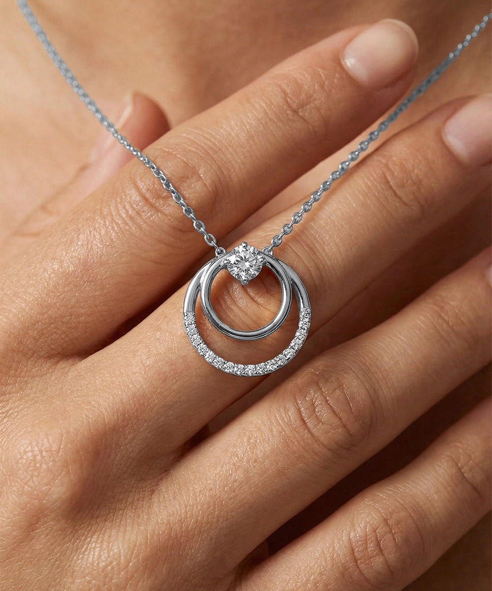 Silver necklace with a circular pendant on a hand