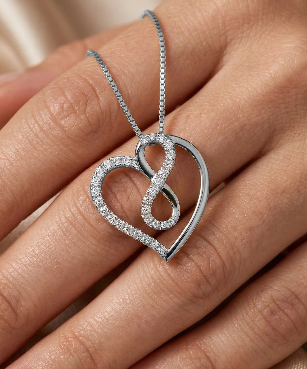 Silver heart-shaped pendant on a chain held in a hand