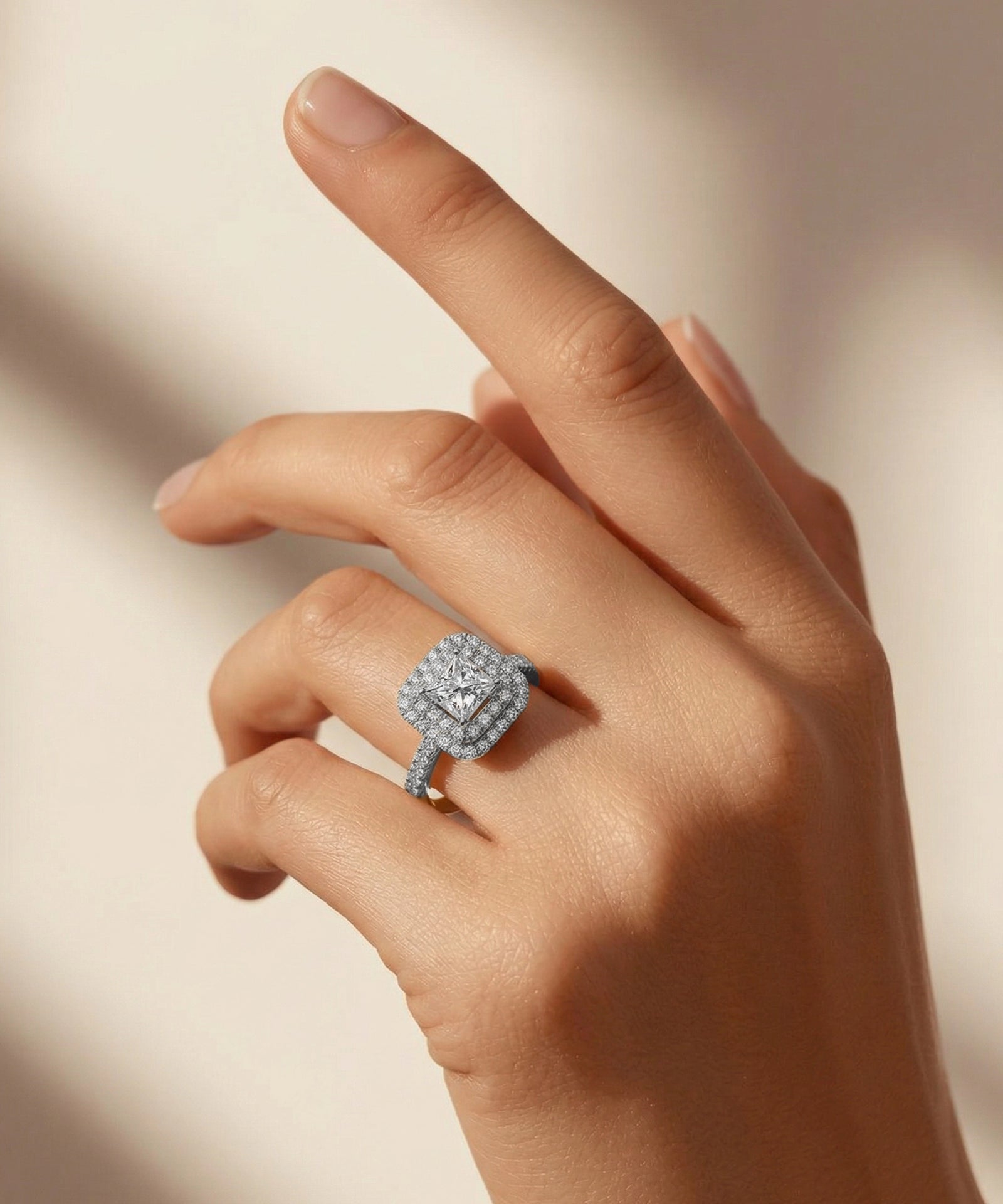 Hand wearing a diamond ring on a neutral background