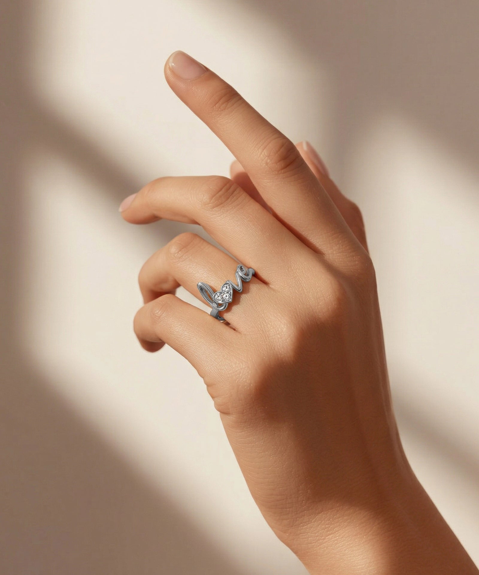 Hand wearing a silver ring with a butterfly design on a neutral background