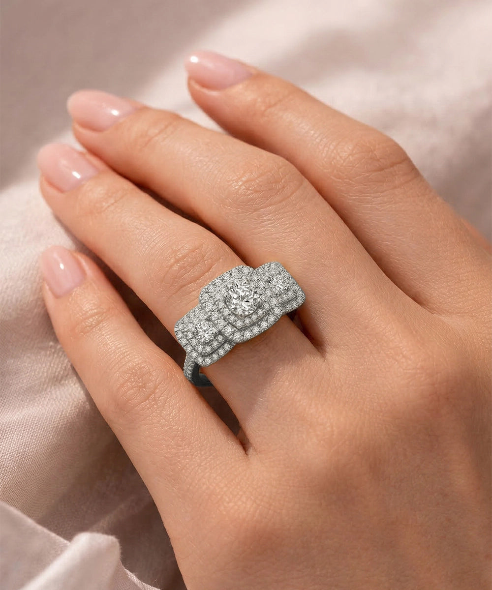 Silver ring with diamonds on a hand against a soft pink background