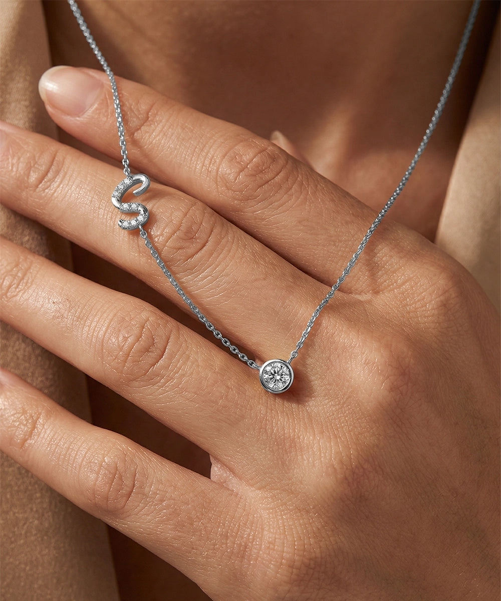 Silver necklace with a pendant held by a hand against a neutral background