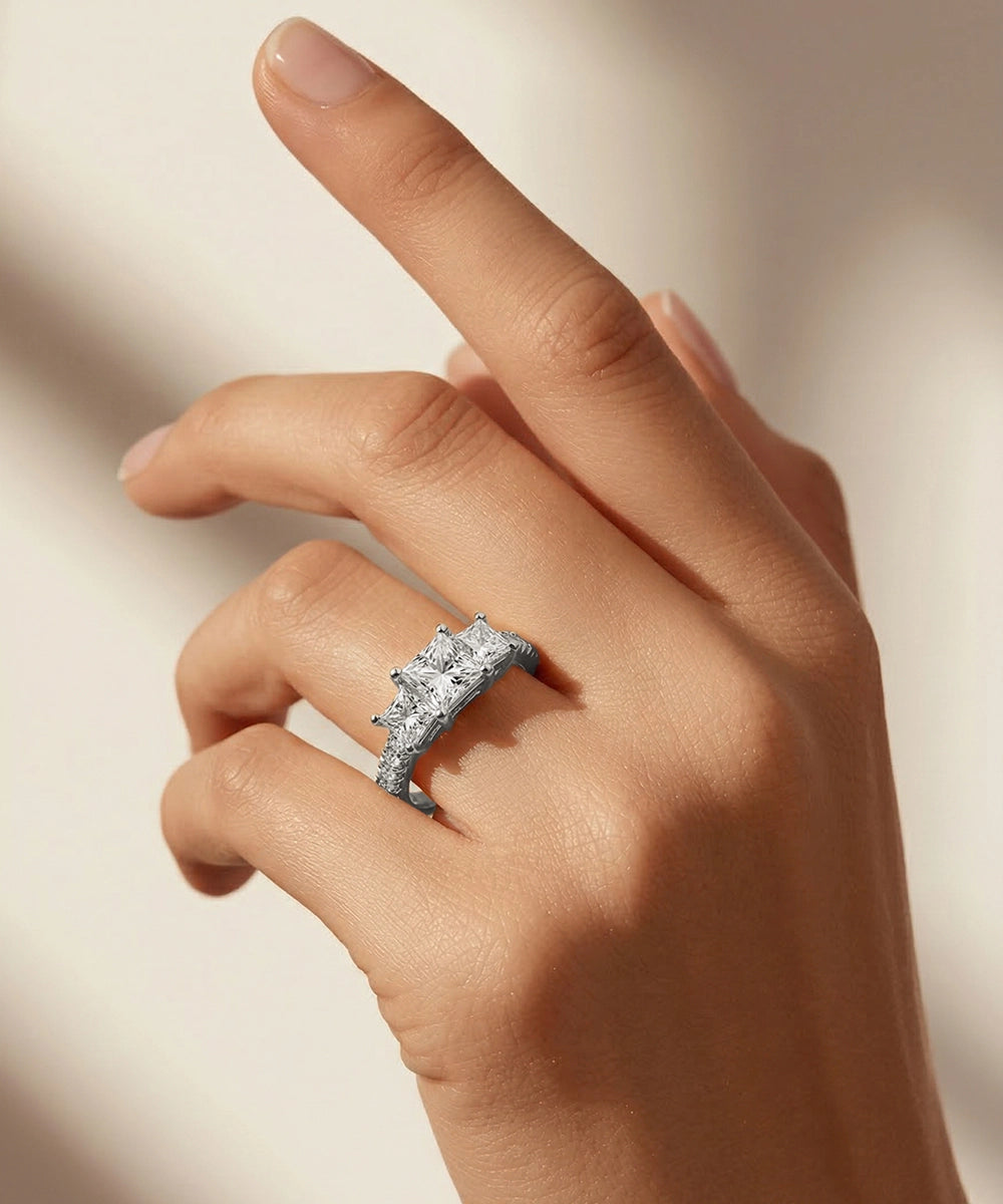 Hand wearing a diamond ring on a neutral background