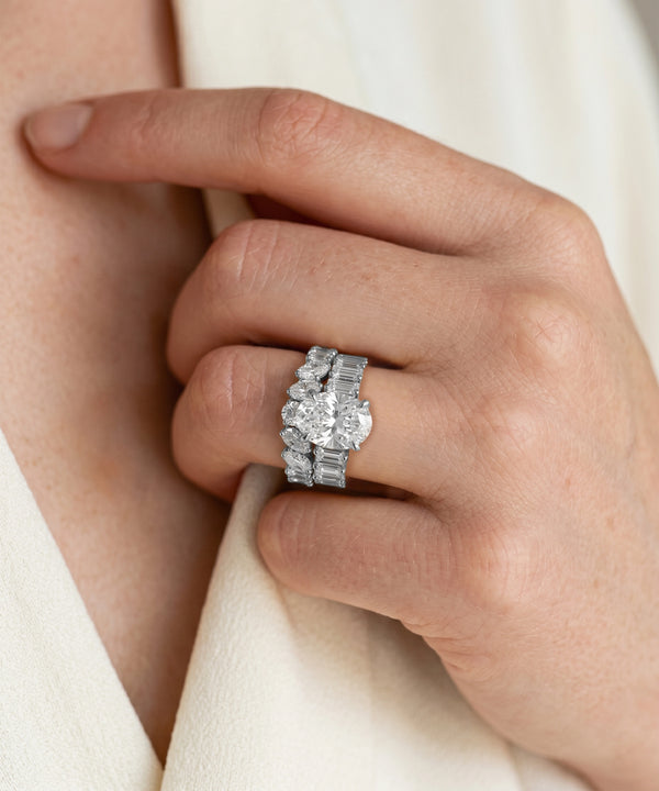 Close-up of a hand wearing a silver ring with multiple diamonds on a light background