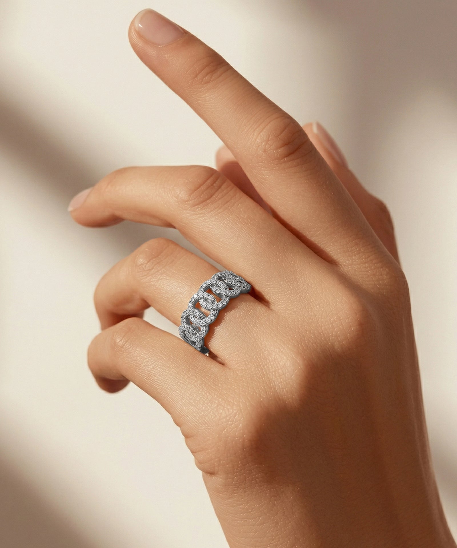 Hand wearing a diamond ring on a neutral background