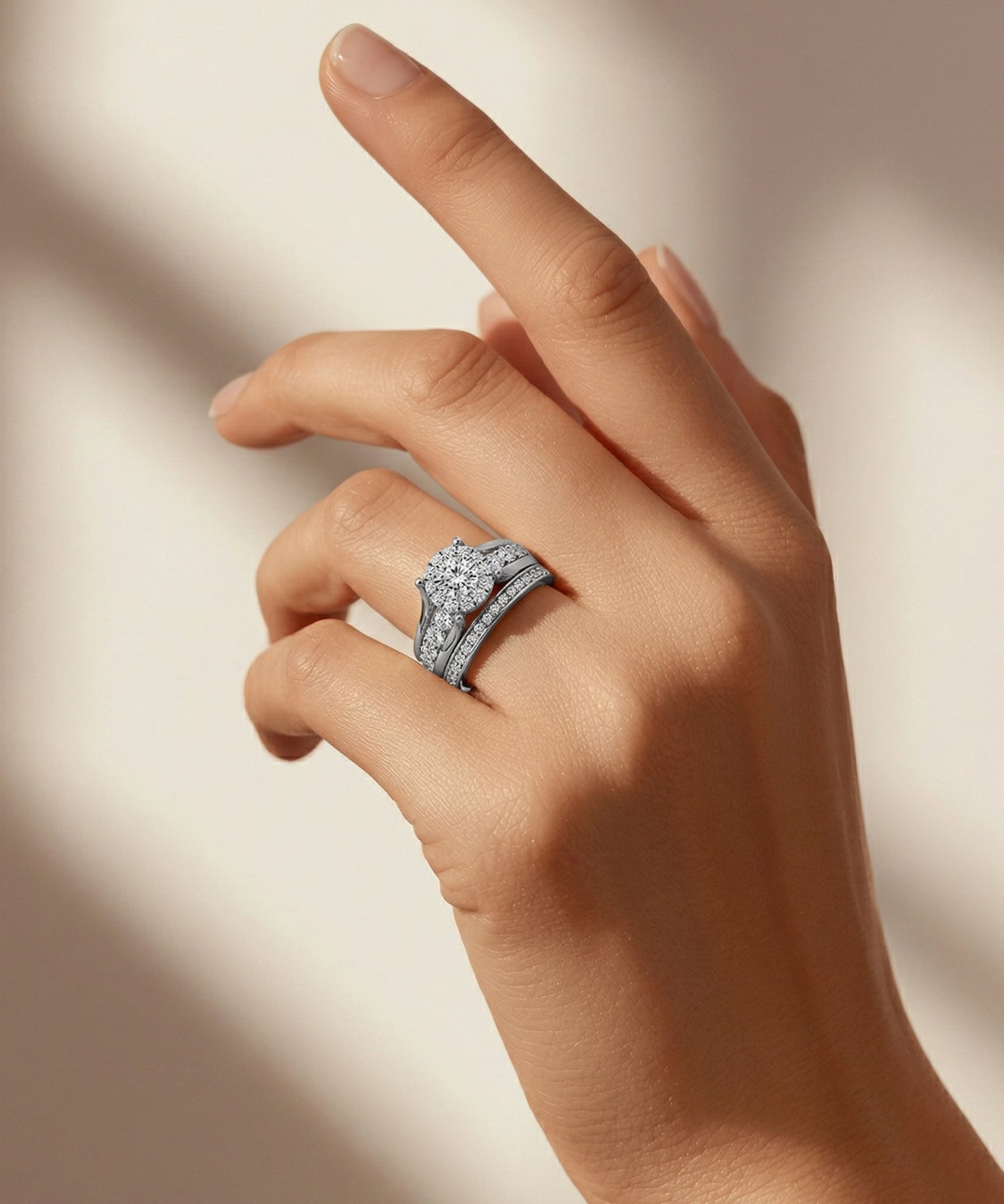 Hand wearing a diamond ring on a neutral background