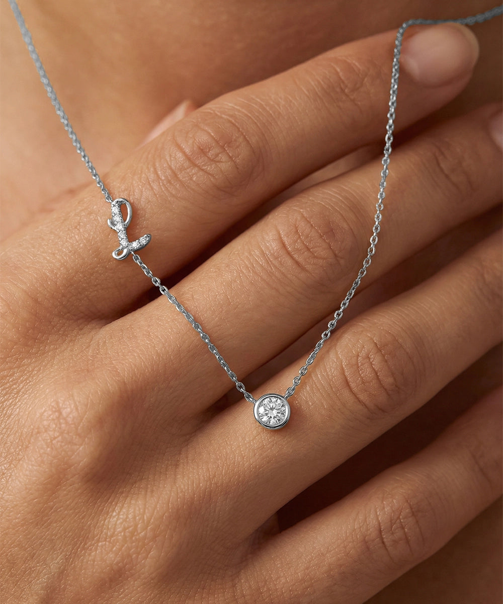 Silver necklace with a pendant on a hand against a neutral background