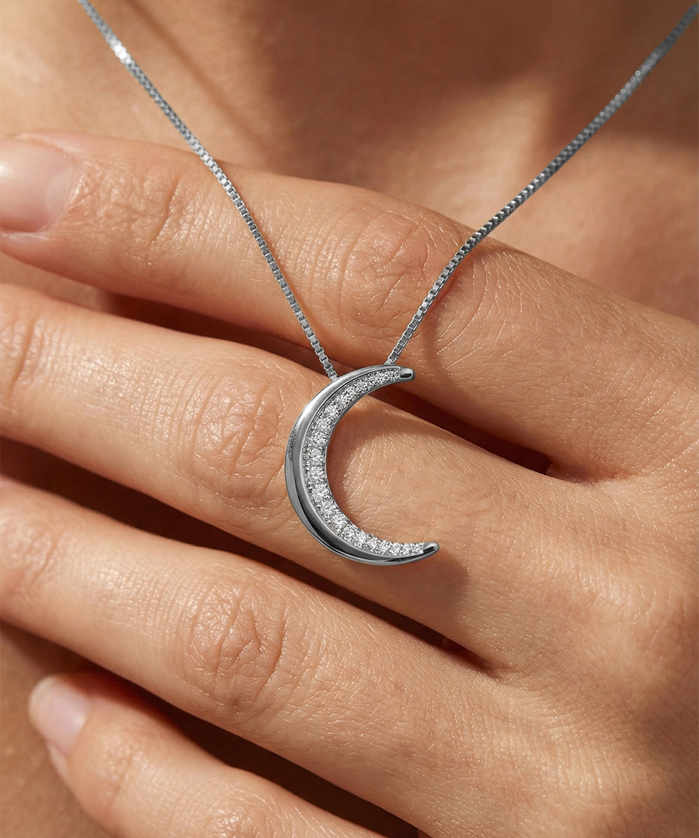 Silver crescent moon necklace on a hand