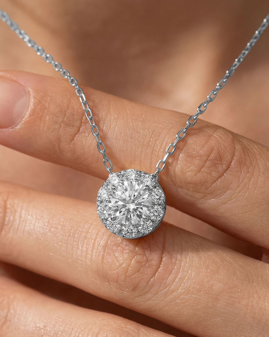 Diamond necklace held between fingers against a blurred background
