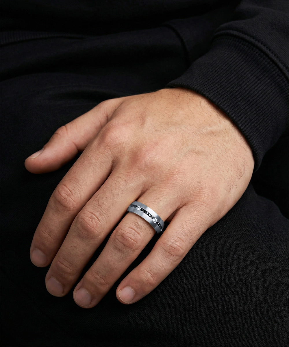 Hand wearing a silver ring with a black background