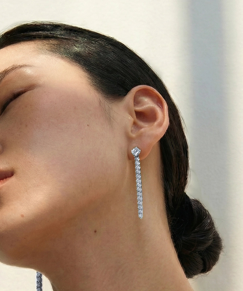 Silver linear diamond drop earring shown on a model.