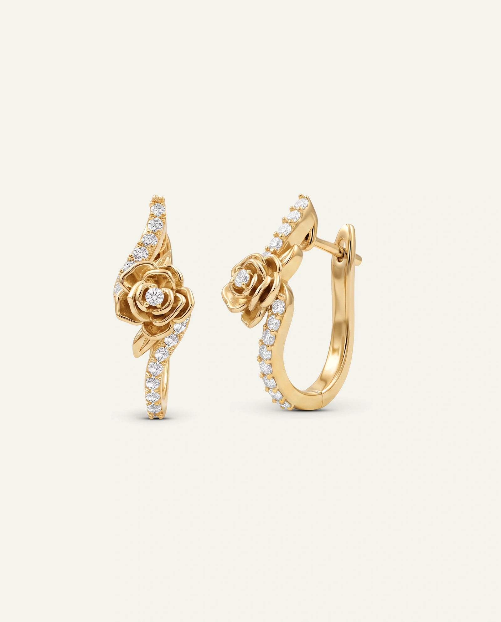 A pair of gold huggie hoop earrings featuring a rose motif and pavé-set clear stones, displayed on a light cream background.