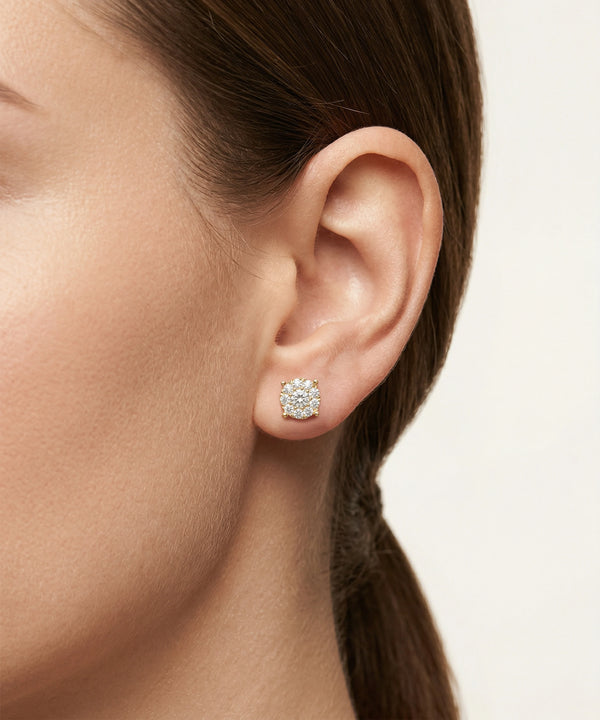 Close-up of an ear wearing a diamond earring with a neutral background