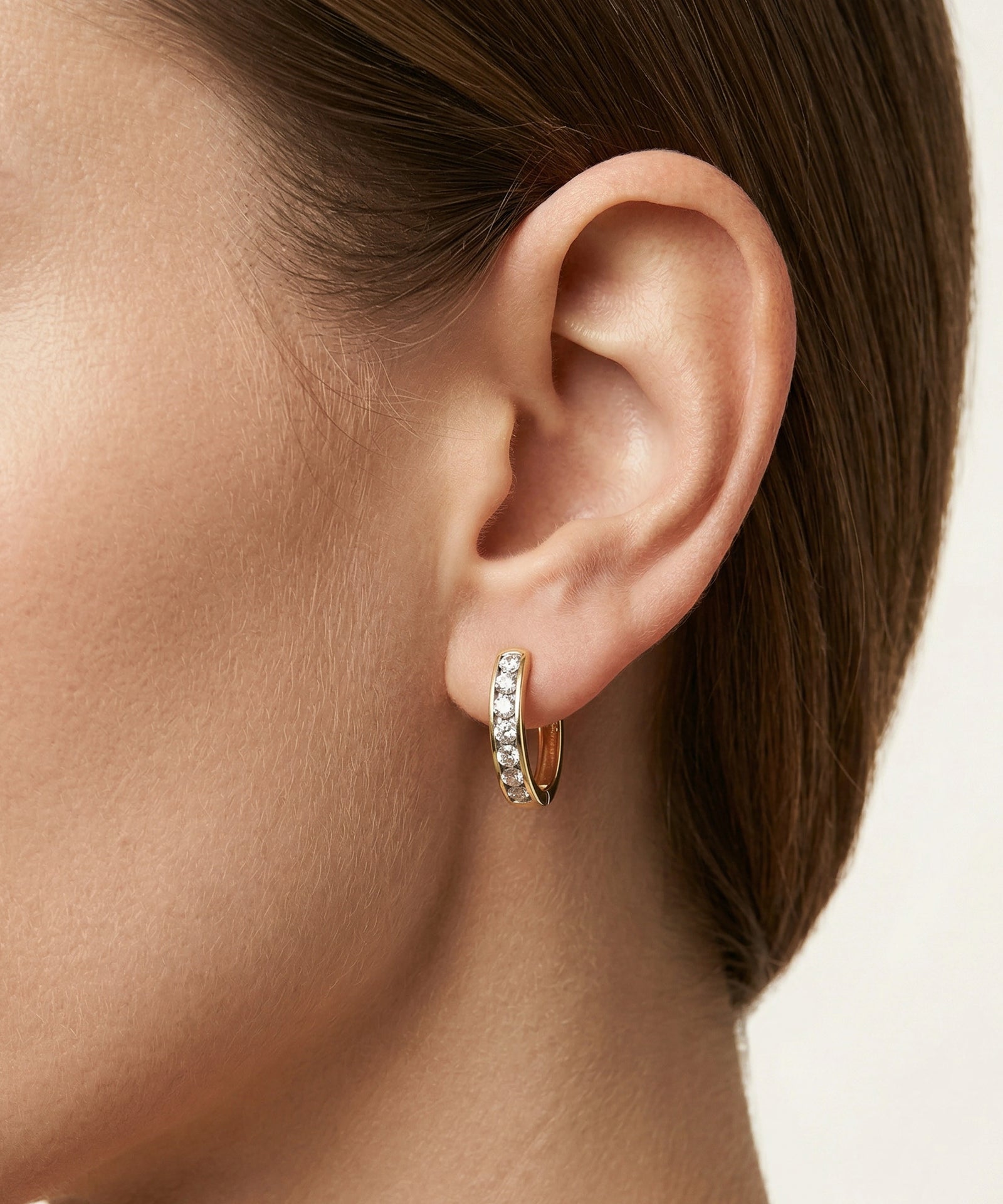 Close-up of an ear wearing a silver hoop earring with a blurred background