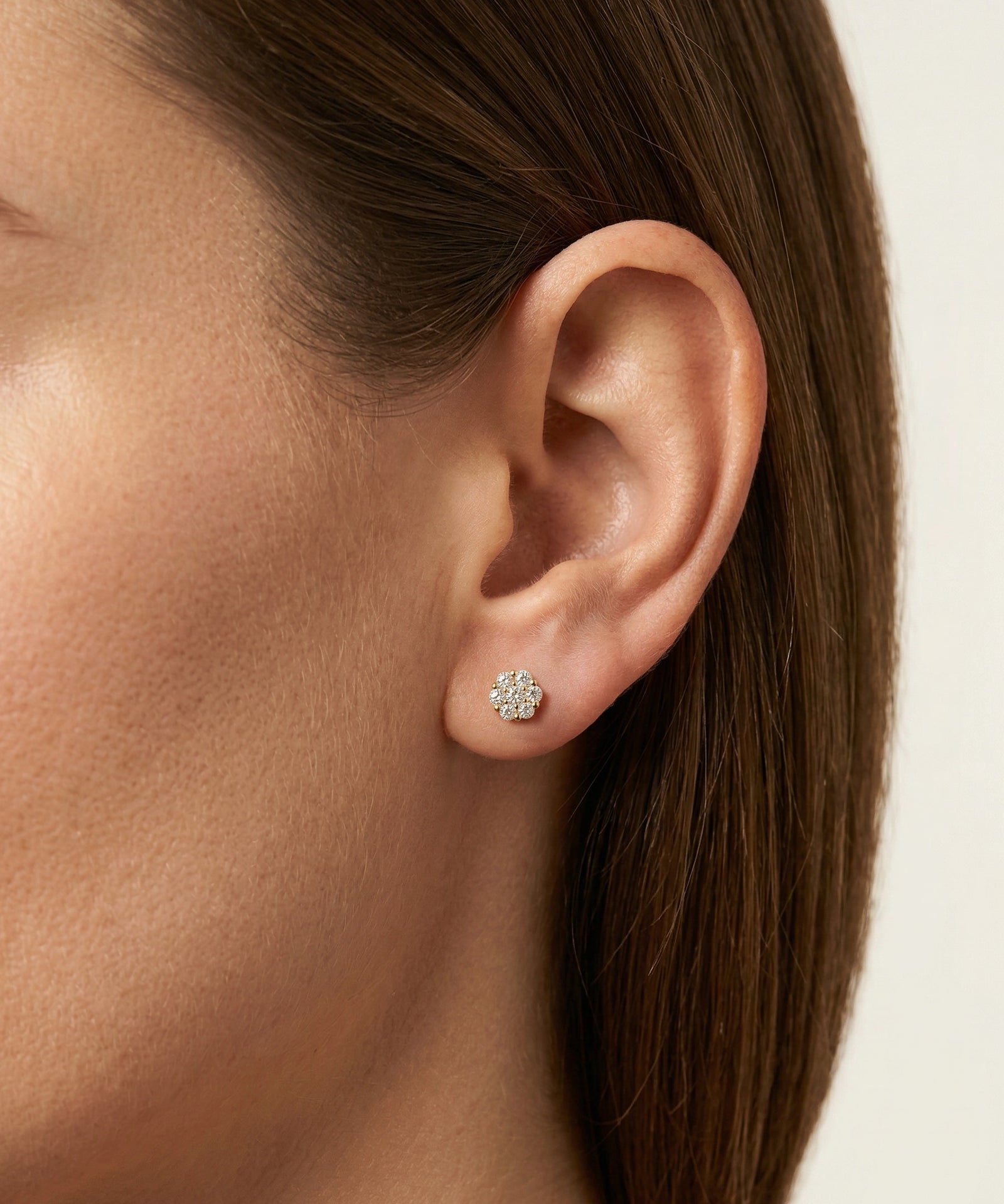 Close-up of an ear wearing a floral earring with a plain background