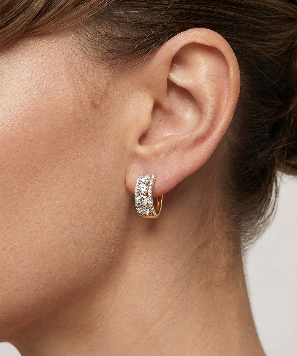 Close-up of an ear wearing a silver hoop earring with clear gemstones.
