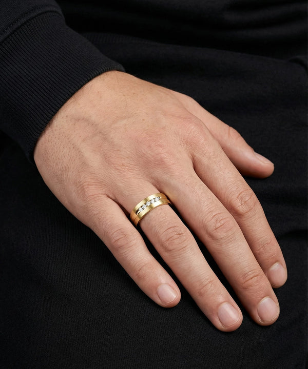 Hand wearing a gold ring on a black background