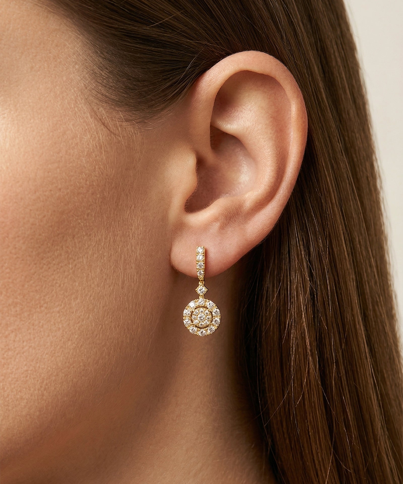 Close-up of a diamond earring worn by a person with brown hair.