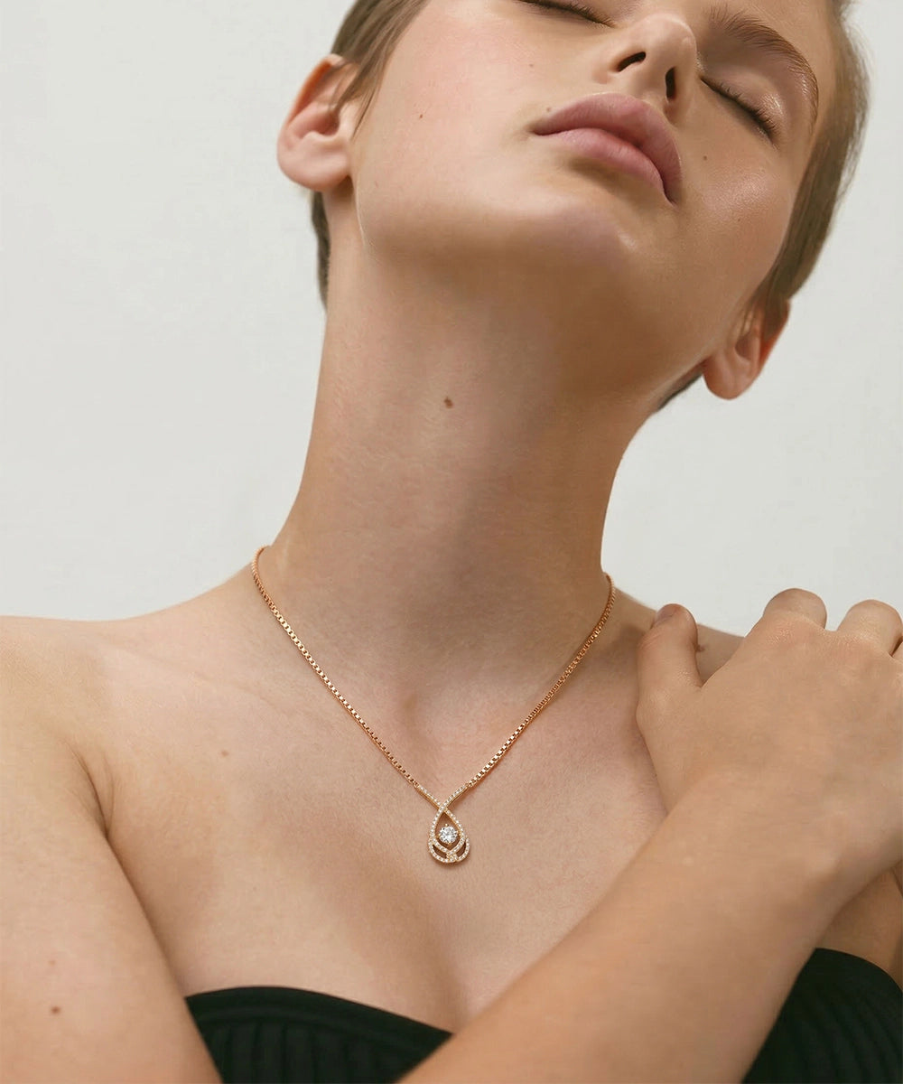 Woman wearing a delicate necklace with a small pendant against a neutral background
