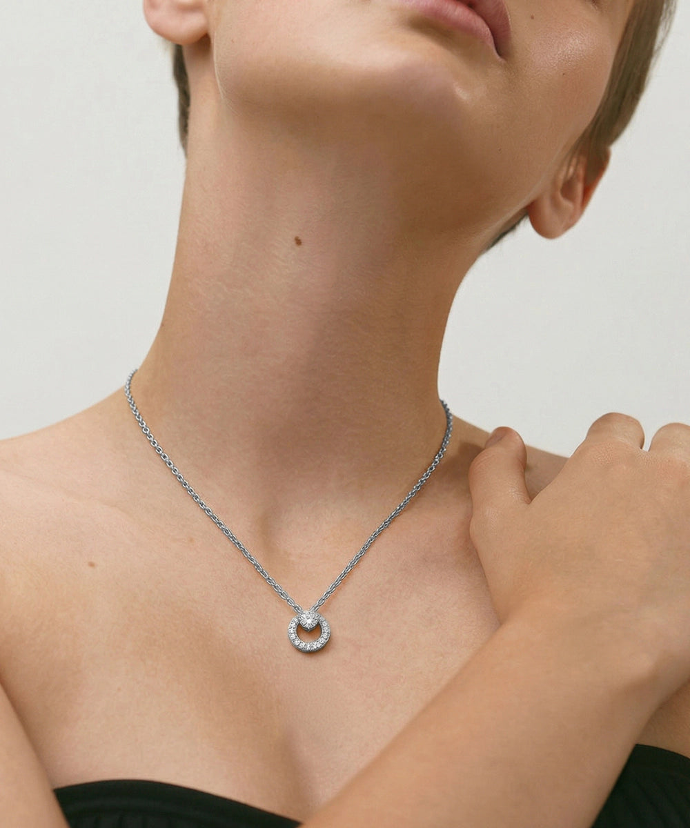 Necklace with a circular pendant worn by a person against a neutral background
