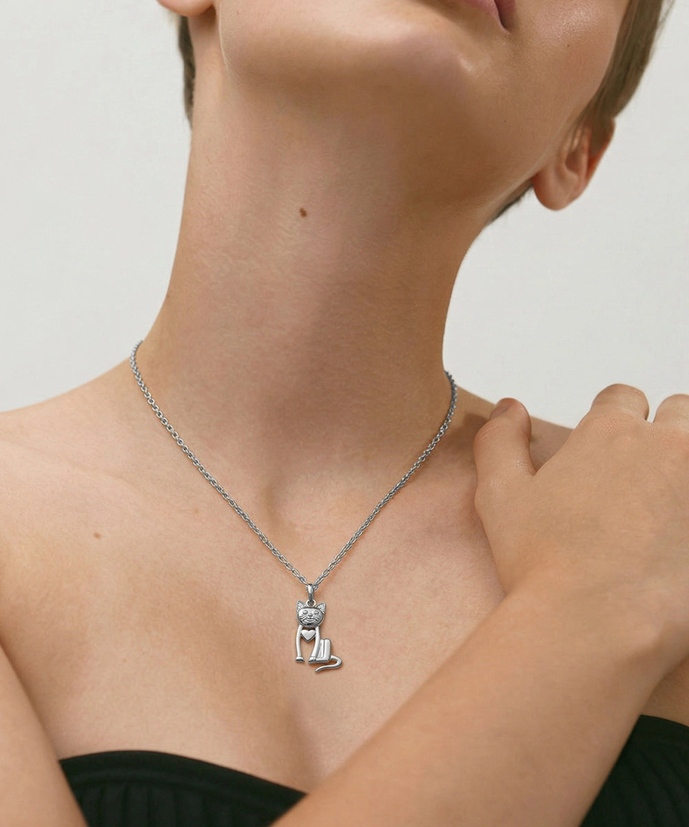Person wearing a silver necklace with a cat pendant on a plain background