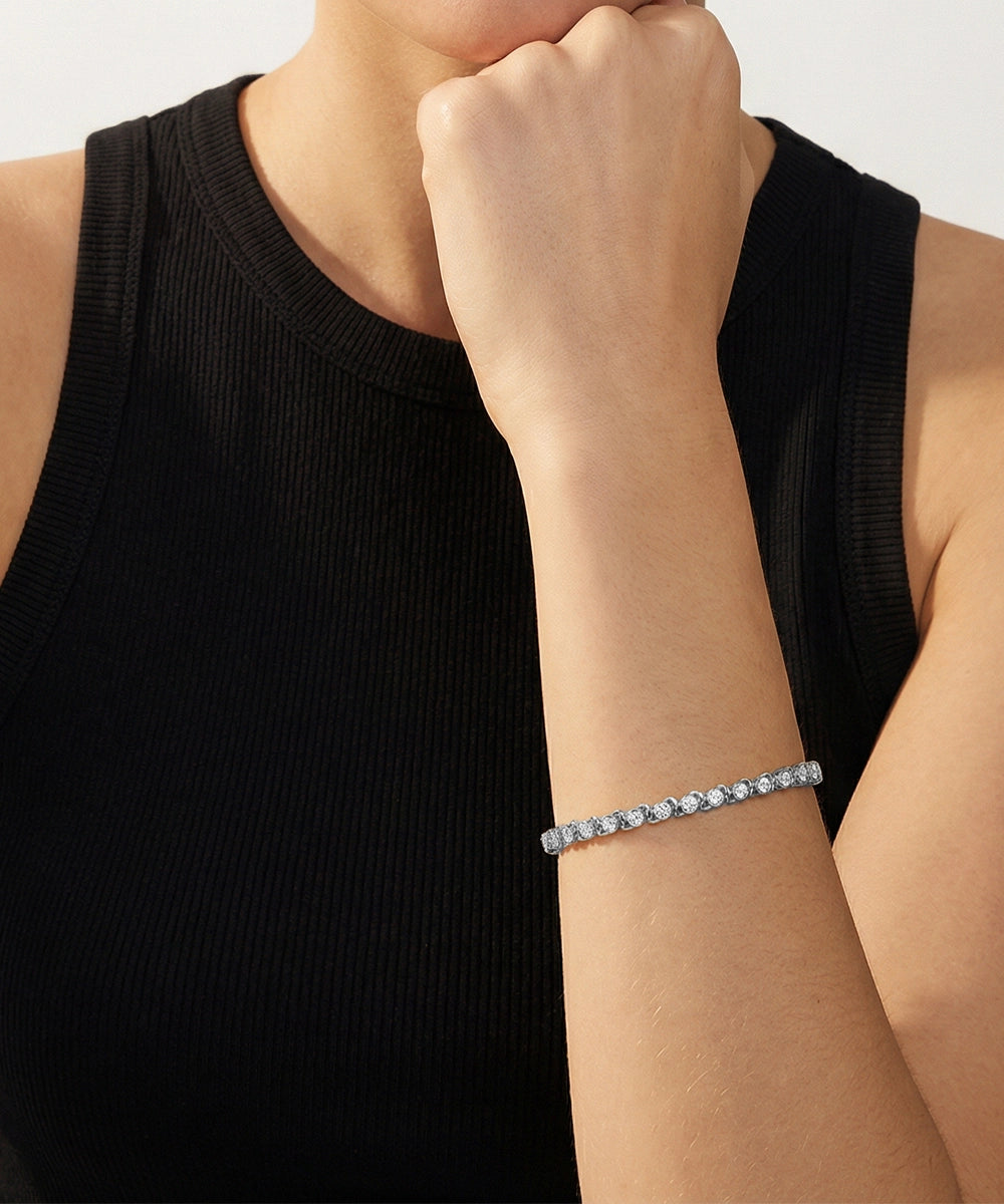 Person wearing a black sleeveless top with a bracelet on a neutral background